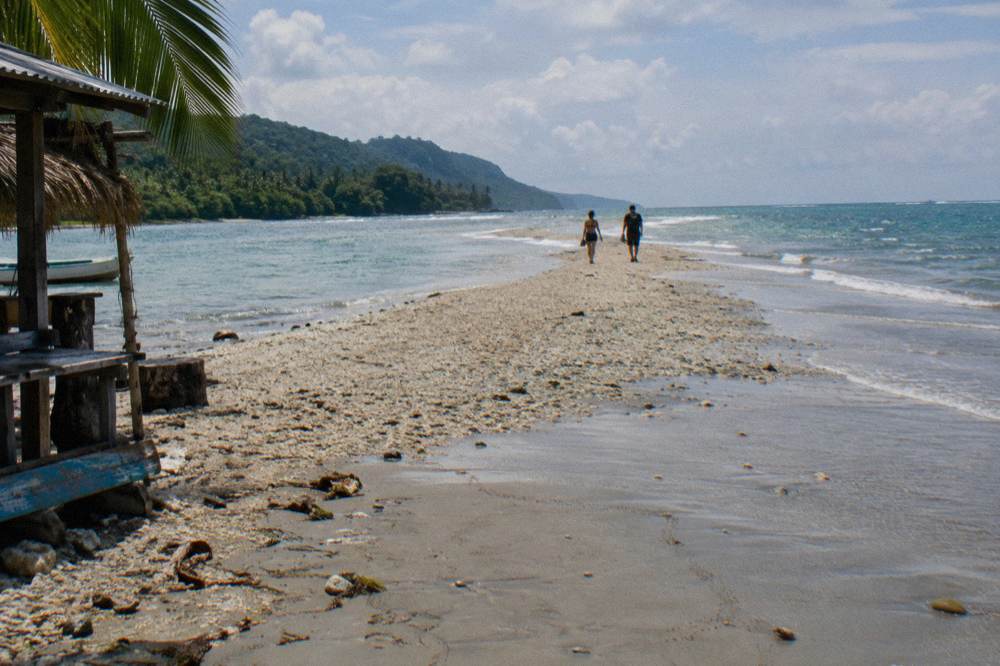 Long sandbar extending into turquoise ocean at low tide shaped like a whale tail
