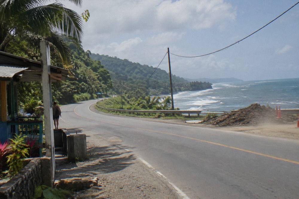 A coastal road curving along green hills above the Pacific ocean