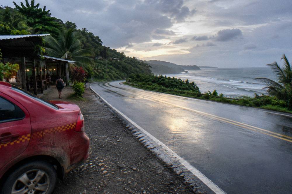 A coastal highway curving along green hills above the ocean