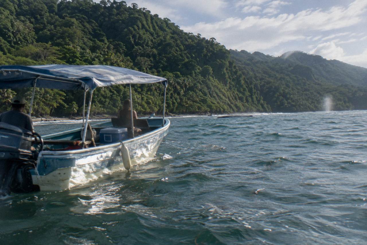 A boat on calm Pacific water near forested hills at Marino Ballena National Park