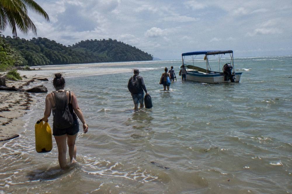 Tour boat anchored in shallow water near a sandbar at low tide