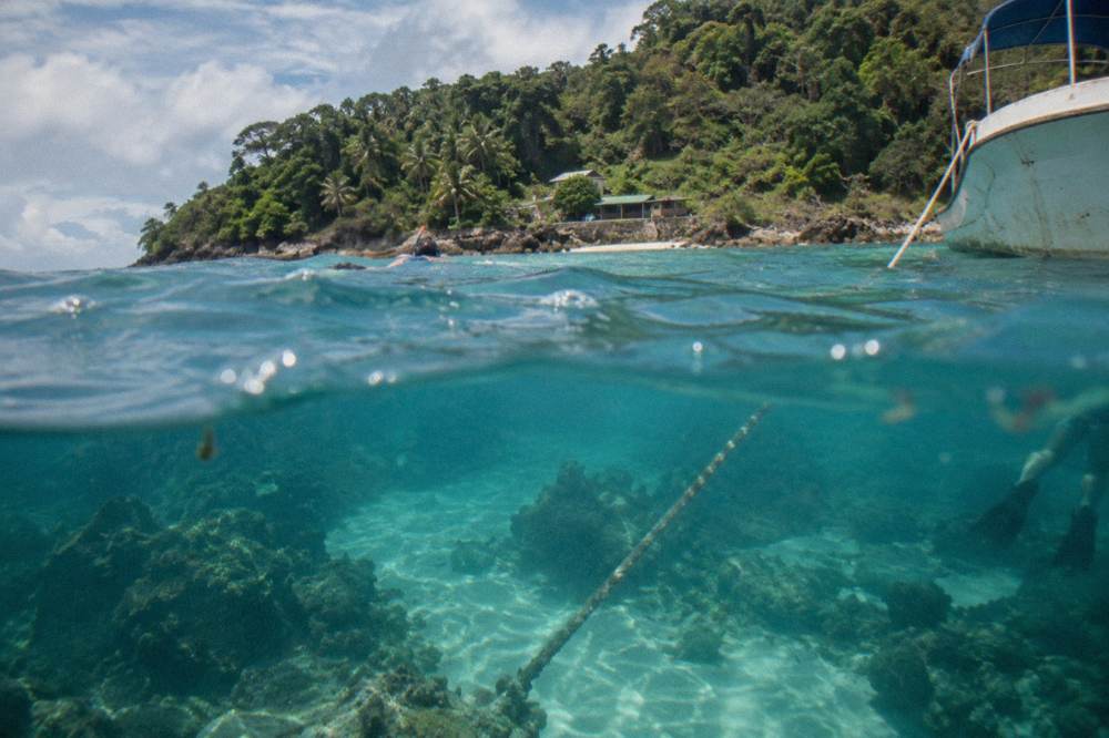 Anchor rope and coral formations seen through clear turquoise water from the surface