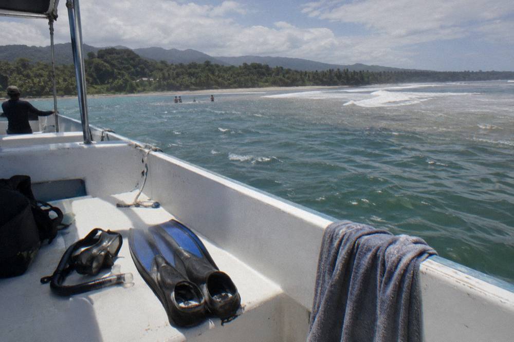 Snorkel fins and mask drying on the deck of a small tour boat in bright sunlight