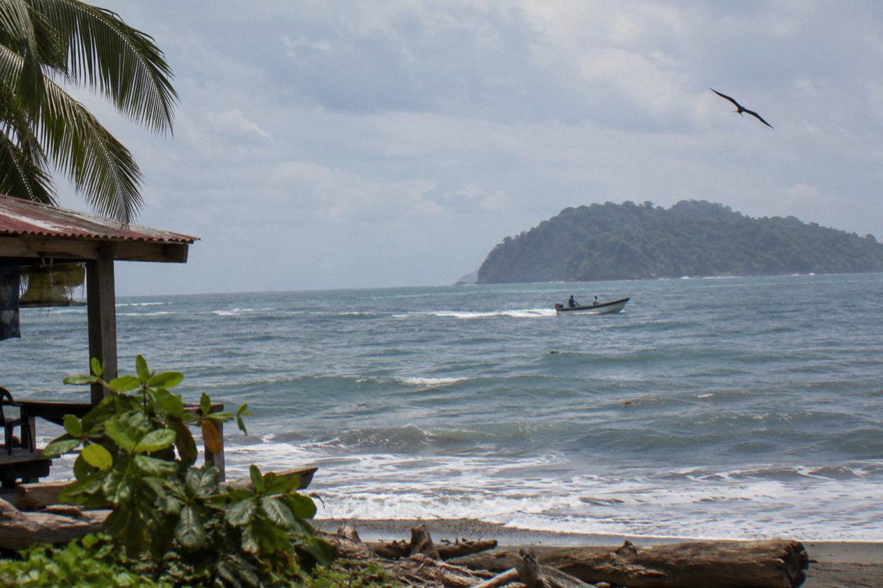 Open Pacific water off Uvita with a small boat crossing toward a forested island