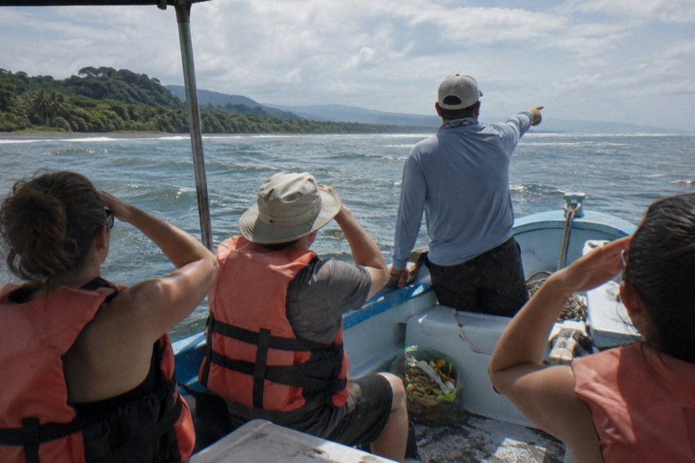 A guide pointing toward the horizon from the deck of a tour boat