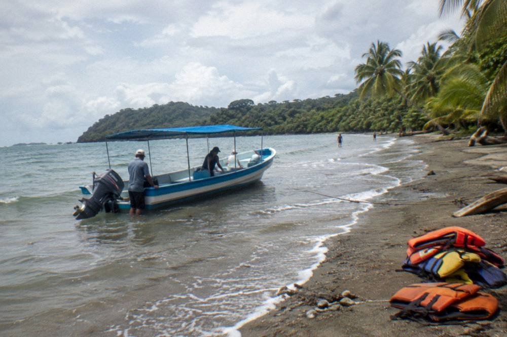 A calm sandy beach with a tour boat pushed into shallow water at the shoreline