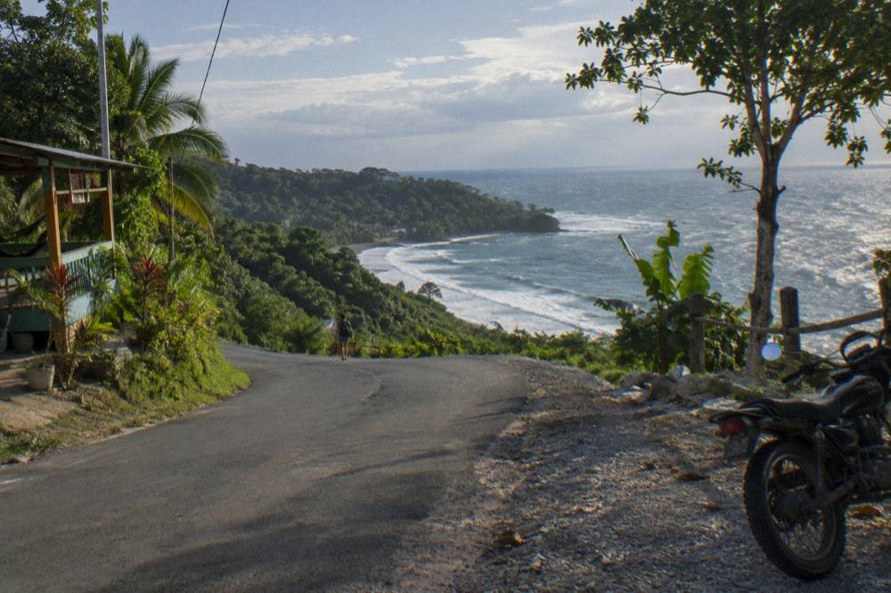 Winding coastal road above a green shoreline with the ocean beyond