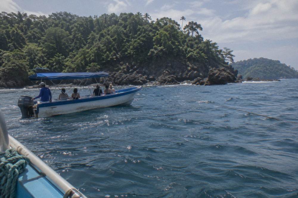 A tour boat anchored near a rocky island in blue ocean