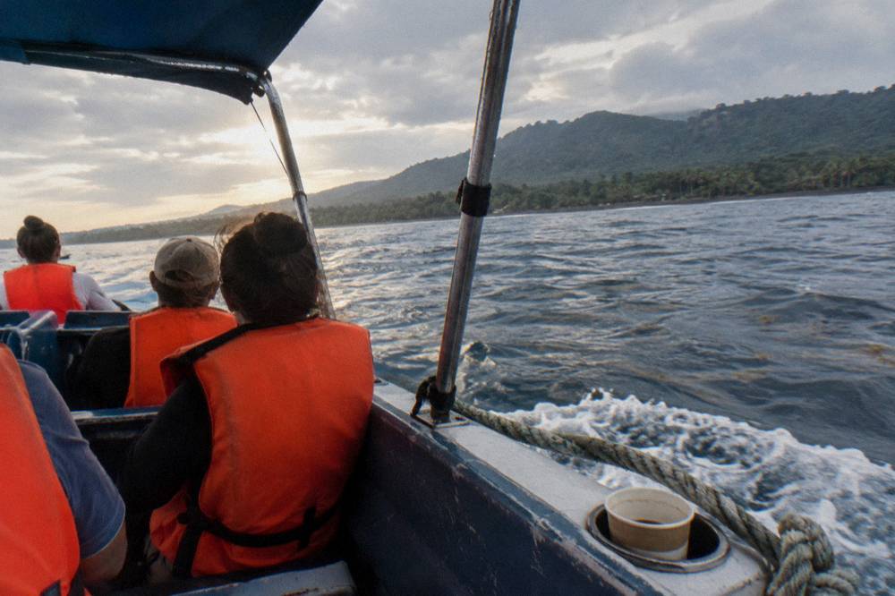Passengers in life jackets watching the water from a boat deck