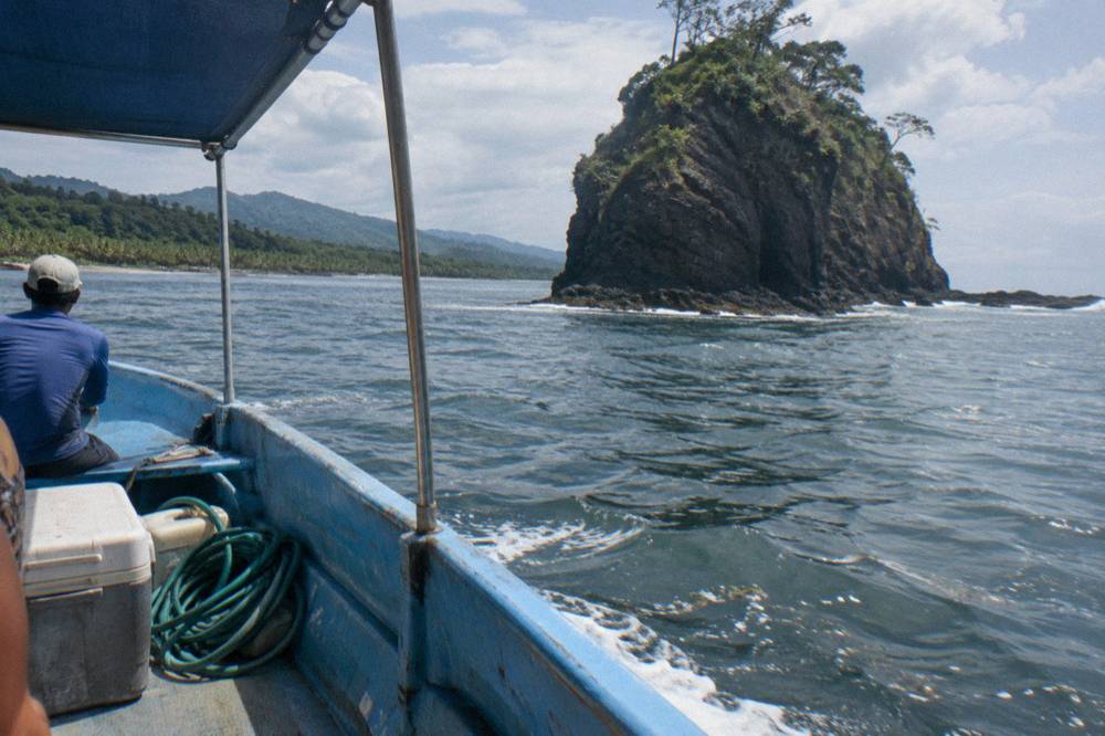 Small open tour boat riding calm water near a rocky island coastline