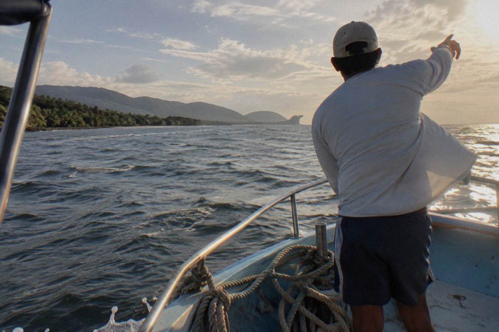 Tour guide pointing toward open ocean from the bow of a boat