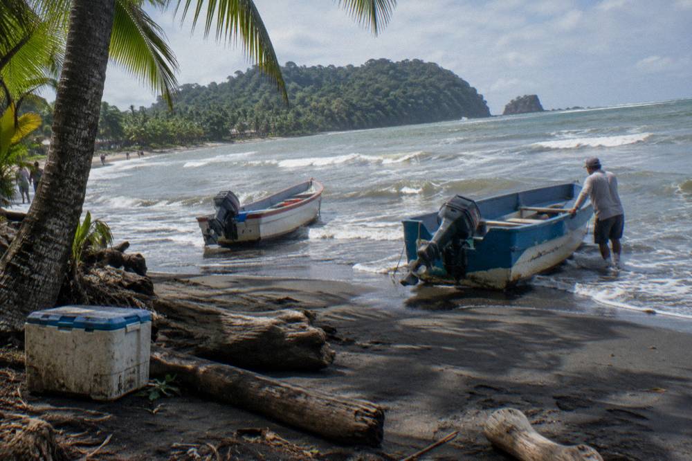 Beach with boats pulled onto the sand near a park entrance sign