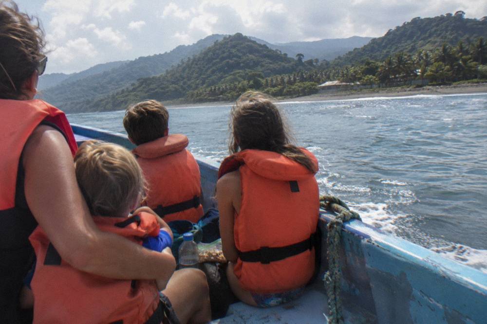 Family group in life jackets seated along the side of a small tour boat