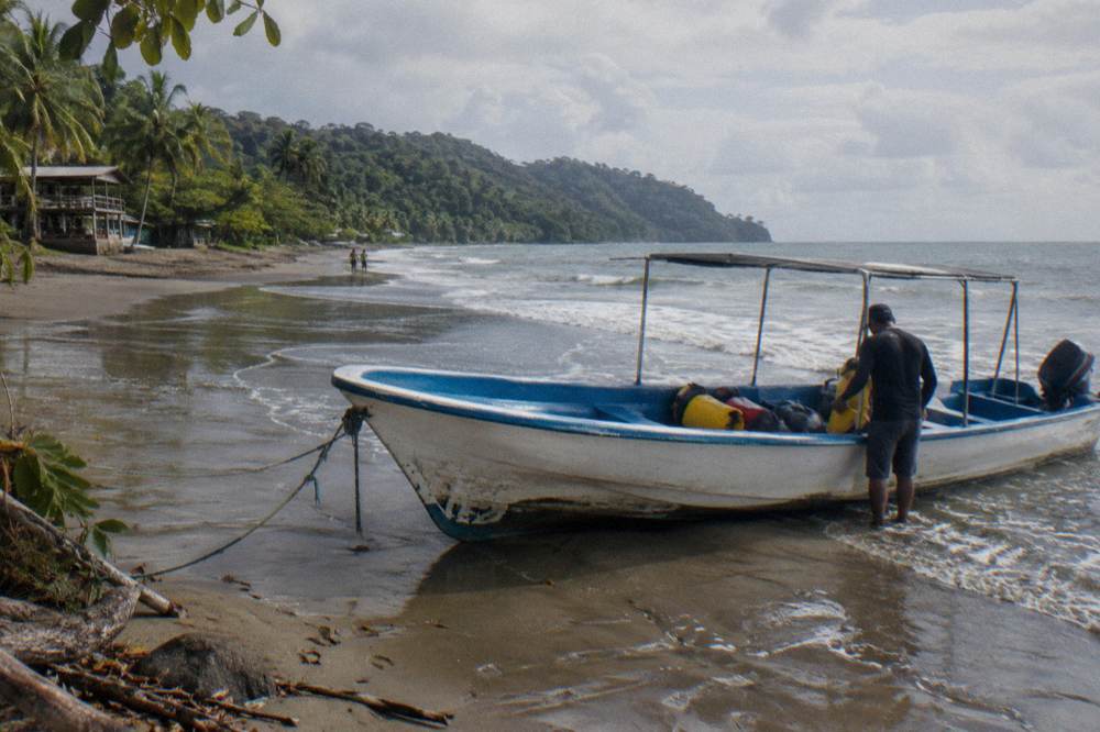 A tour boat resting on a sandy beach beside calm morning water