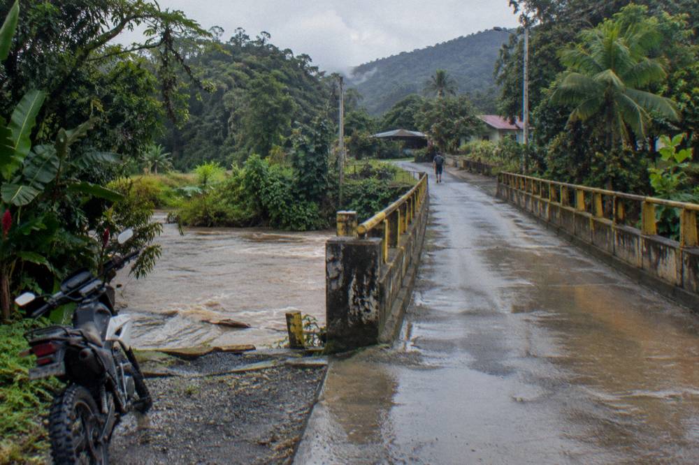 A two-lane highway bridge crossing a river between forested hills