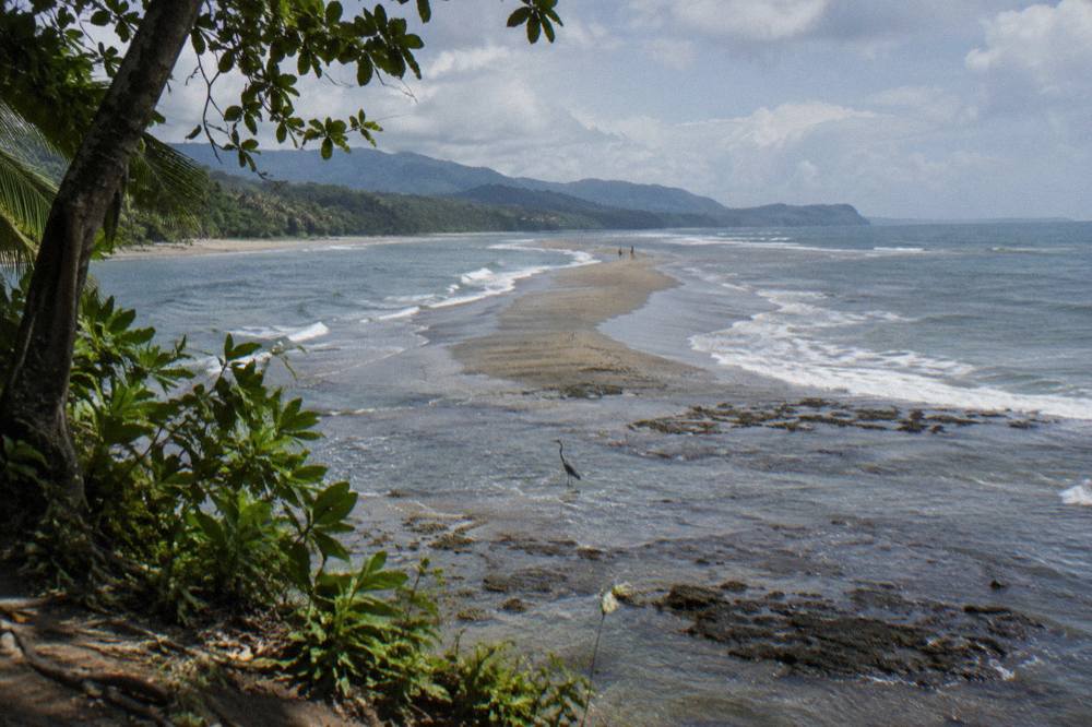 Long sandbar curving into the ocean at low tide with waves on both sides