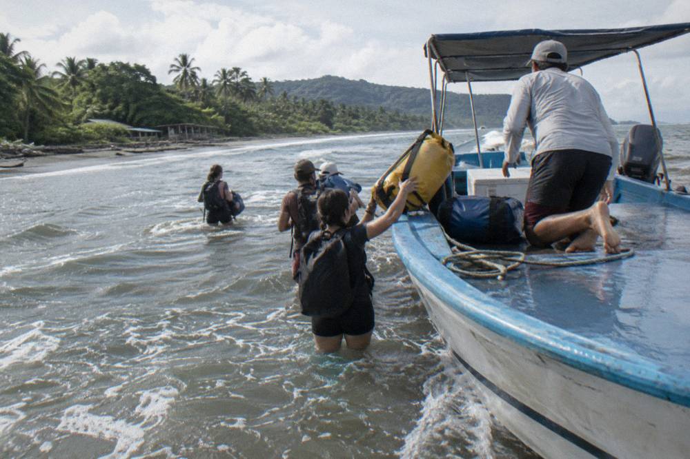 Small tour boat anchored off a tropical beach with passengers boarding