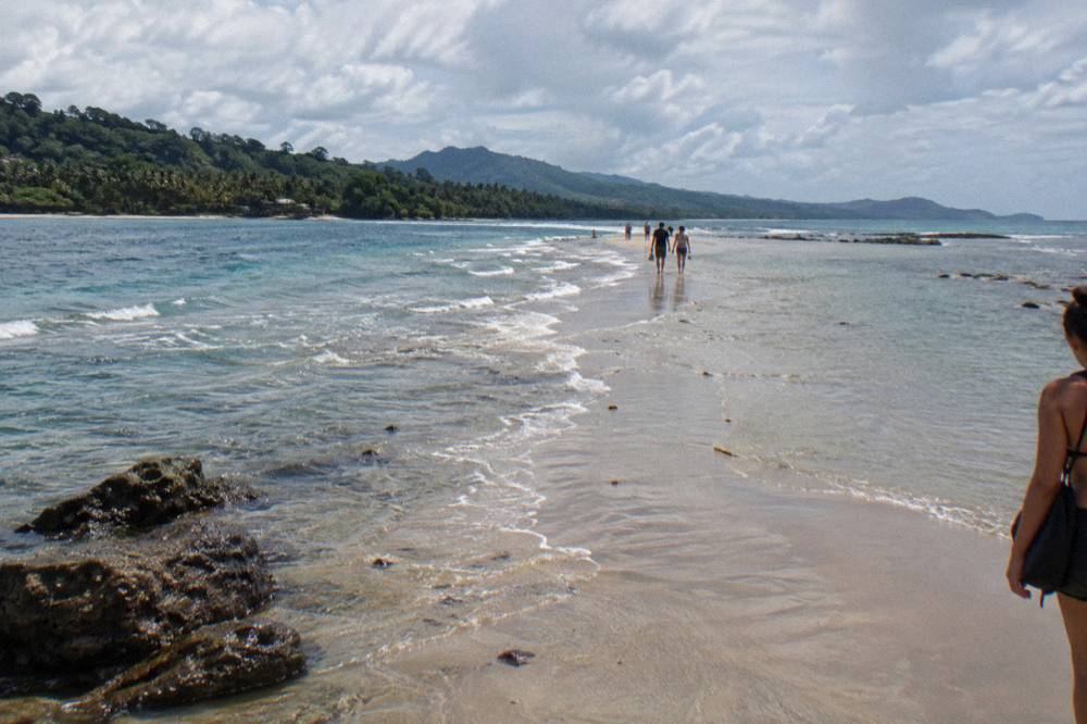 A sandbar ridge extending into turquoise water with gentle waves on both sides