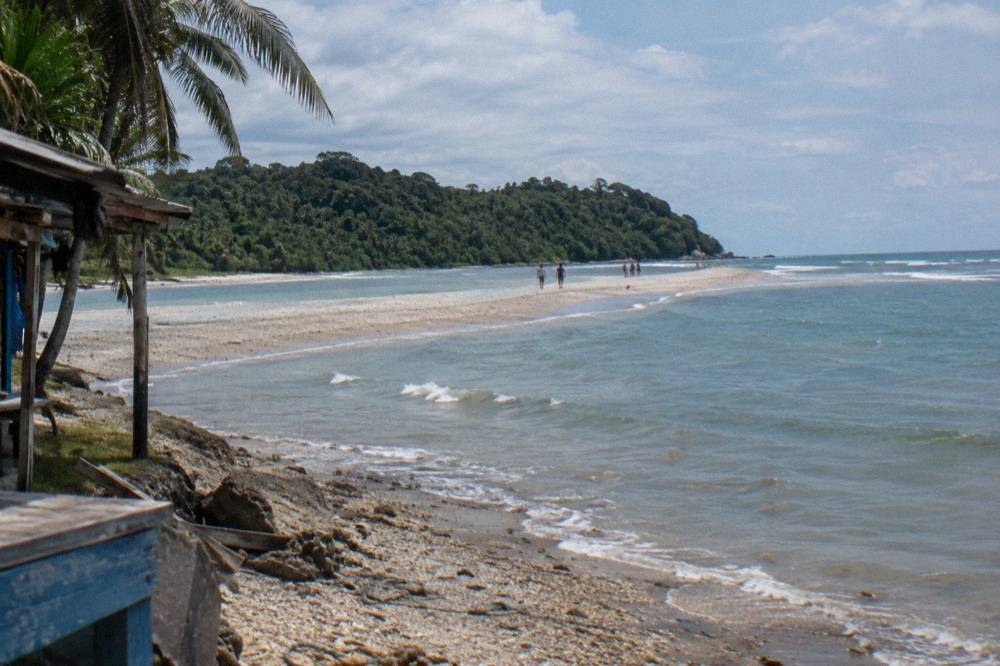 Long sandbar shaped like a whale tail extending into turquoise water at low tide