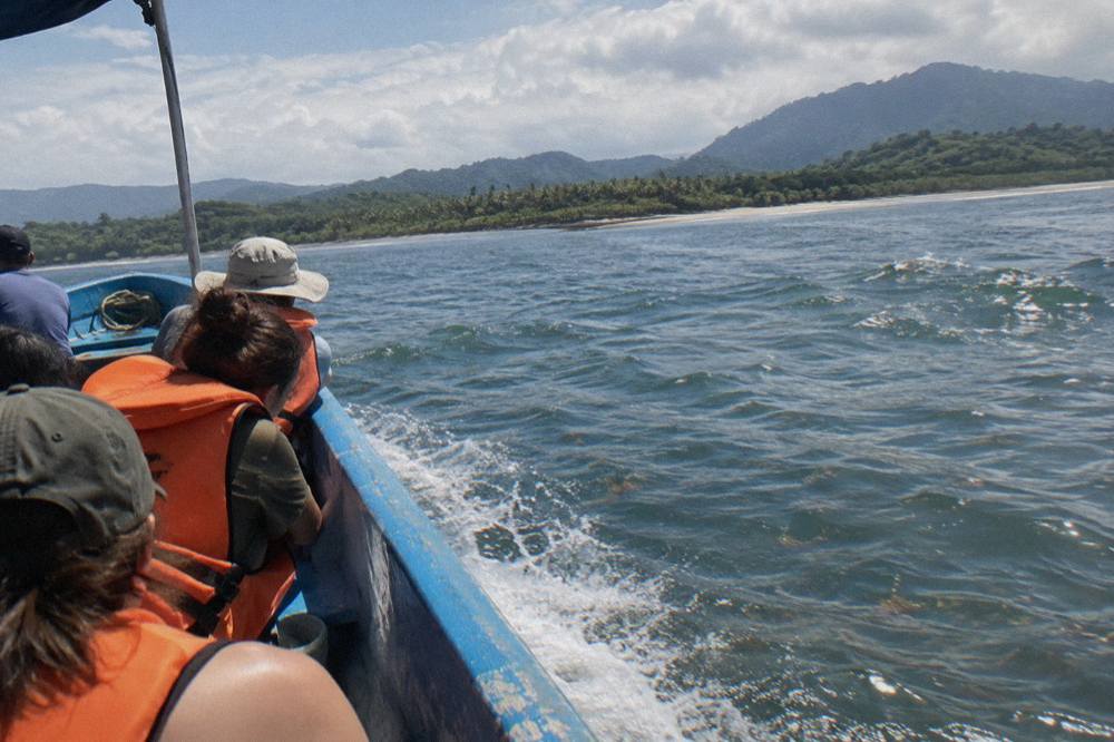 A tour boat crossing open ocean swells with passengers watching the water