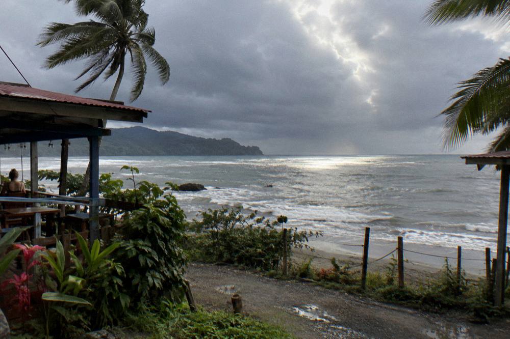 Dark rain clouds over the ocean with a patch of sunlight on the water